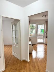 ポビエロボにあるApartament MOKKAの白い壁とウッドフロアの空きリビングルーム