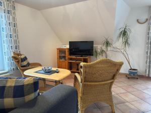 Una sala de estar con una mesa y sillas y un televisor. en Graal-Müritz Garden Balcony Stay, en Graal-Müritz