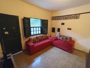 a living room with two red couches and a window at República Engenho Quarto Casal in Ouro Preto +1 photo