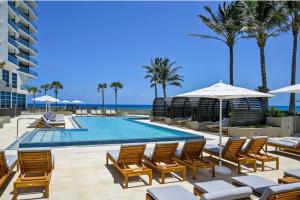 una piscina sulla spiaggia con sedie e ombrelloni di Luxury Ocean View 2BR a Riviera Beach