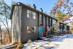 a wooden house with a blue door in the snow at Cozy Smoky Mountain Escape w/ Private Deck & Community Pool in Pigeon Forge