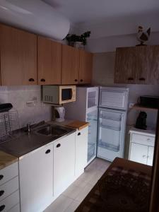 a kitchen with white cabinets and a sink and a refrigerator at Casa Maria T1 in Armação de Pêra