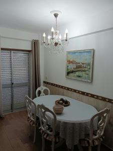 a dining room with a table with chairs and a chandelier at Casa Maria T1 in Armação de Pêra +8 photos