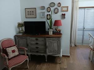 a living room with a television on a wooden dresser at Casa Maria T1 in Armação de Pêra