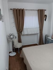 a bedroom with a bed and a window with a fan at Casa Maria T1 in Armação de Pêra
