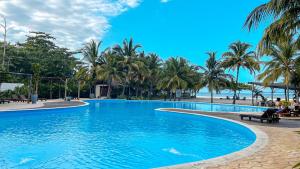 Una gran piscina con palmeras y una playa. en Tay Beach Hotel Tayrona, en Buritaca