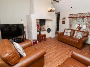 een woonkamer met lederen meubels en een flatscreen-tv bij Tile Rouge in Wooler