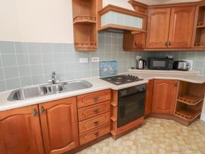 a kitchen with wooden cabinets and a sink at Manor Cottage in Wooler