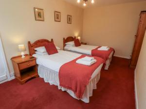 two beds in a room with red carpet at Manor Cottage in Wooler +35 photos