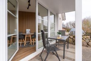 une extension en verre d'une maison avec une table et des chaises dans l'établissement Ferienwohnung Four Twee – Ihr gemütlicher Rückzugsort in SPO, à Sankt Peter-Ording