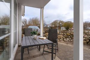 une table et des chaises en bois sur une terrasse dans l'établissement Ferienwohnung Four Twee – Ihr gemütlicher Rückzugsort in SPO, à Sankt Peter-Ording
