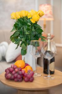 a table with a vase of yellow roses and wine glasses at Gold Apartments NMP 35 in Częstochowa