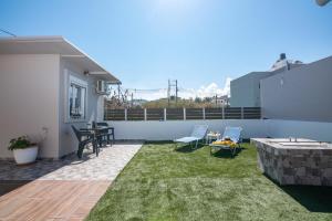eine Terrasse mit Gras, 2 Stühlen und einem Tisch in der Unterkunft Margie's Apartments in Kissamos