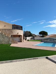 ein Steinhaus mit Swimmingpool und grünem Gras in der Unterkunft Villa Les Grenadines RDC in Mèze
