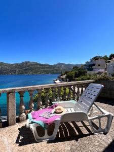 a white chair sitting on a balcony with a table at Beachfront Apartment Mery, Kneže in Račišće