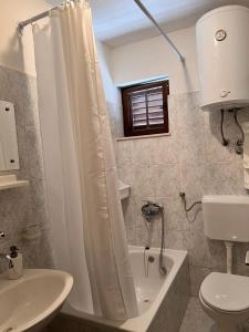 a bathroom with a white shower curtain and a toilet at Beachfront Apartment Mery, Kneže in Račišće +7 photos