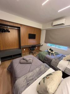 a bedroom with three beds and a flat screen tv at Travellar Spot 12 in Ribeirão Preto