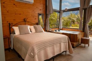 a bedroom with a bed and a bath tub next to a window at Cabanas Jardim dos Canyons in Praia Grande