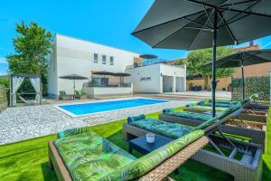 a pool with chairs and umbrellas in a backyard at Villa Nikoma in Dicmo