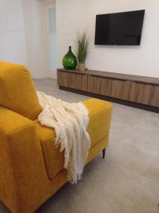a living room with a yellow couch with a blanket at CORTE dei SANTI suite in Lèvego
