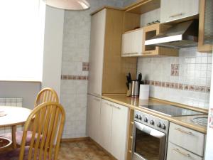 cocina con armarios blancos, mesa y fogones en Stasys Apartments Pilies Street, en Vilna
