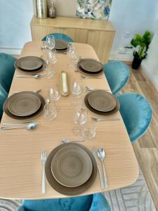 a wooden table with plates and wine glasses on it at La belle échappée, maison chic près de lille & Parc Barbieux in Roubaix +39 photos