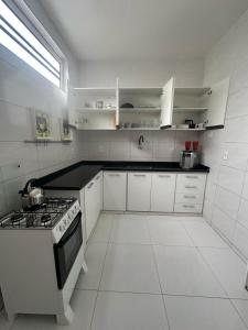 a white kitchen with a stove and white cabinets at Torquato Flats Orla in Petrolina +41 photos