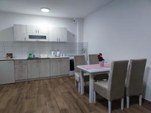 a kitchen with a table and chairs and a kitchen with white cabinets at Apartman Tara 2 in Sremska Mitrovica +3 photos