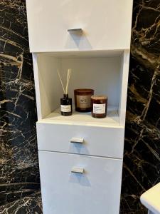 a white cabinet with two jars of candles on it at Magic Place Bergamo! Beauty Nest Apartment in the heart of the city in Bergamo