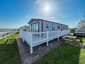 een tiny house met een veranda en een picknicktafel bij Beautiful Caravan With Stunning Sea Views At Haven Hopton Ref 80001H in Great Yarmouth