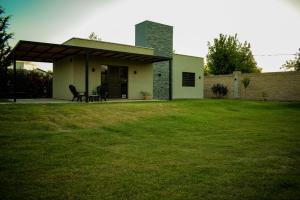 una pequeña casa blanca con un patio de césped en Complejo Zampa - Moderna casa con Pileta y Parque, en San Rafael