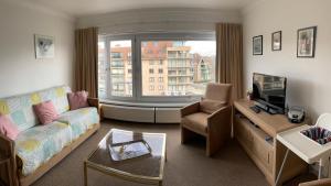 een woonkamer met een bank, een tv en een raam bij Zonnige studio Mermoz Koksijde-Bad in Koksijde