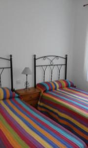 2 camas con sábanas de rayas coloridas en un dormitorio en Madrigal Iruela, en La Iruela