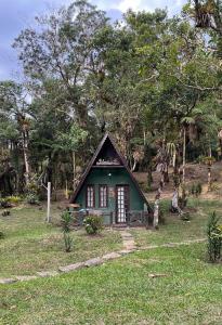 a small green house in a field with trees at A Luz Azul - Pousada e Gastronomia in Bananal