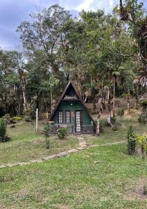 a small green house in a field with trees at A Luz Azul - Pousada e Gastronomia in Bananal