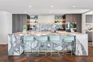 a kitchen with a marble counter and bar stools at Complete Host Nine Elm Apartments in Melbourne +28 photos