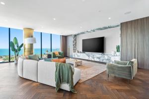 a living room with a white couch and a television at Complete Host Nine Elm Apartments in Melbourne