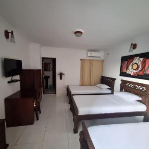 ein Zimmer mit drei Betten und einem Flachbildfernseher in der Unterkunft Hotel Cartagena Comfort in Cartagena de Indias