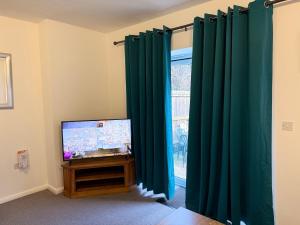 a living room with green curtains and a television at Doctors, Nurses, Families and contractors welcome in Huntingdon