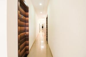 a hallway with white walls and wooden doors at Hotel O Unique Inn in Dhule
