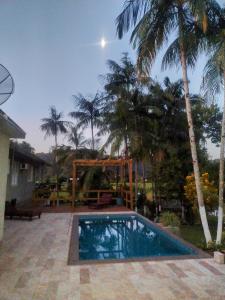 a swimming pool in front of a house with palm trees at Cantinho da nona Nova Trento SC in Nova Trento