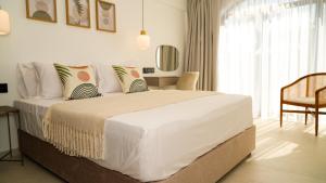 a white bedroom with a large bed and a chair at Sirena Bay Beach House and Luxury Suites in Protaras +27 photos