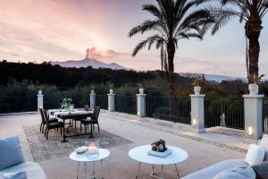 a patio with tables and chairs with a view of a mountain at Donna Carmela Resort & Lodges in Riposto