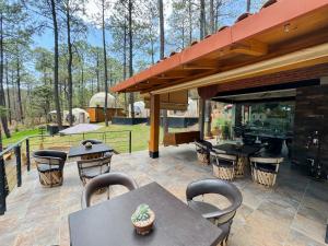 eine Terrasse mit Tischen, Stühlen und einem Grill in der Unterkunft Luahara Glamping Tapalpa - Domo Natural Experience in Tapalpa