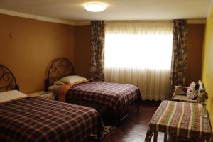 a bedroom with two beds and a window at Posada Kusillos in Puno