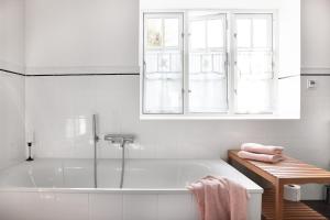 a white bathroom with a tub and a window at Reetdachkate Ölböhm in Giekau +38 photos