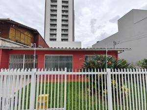 a white fence in front of a red house at Central House in Itajaí