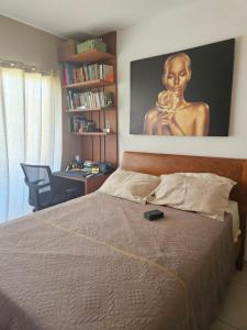a bedroom with a bed with a painting on the wall at Chalé das Conchas in Cabo Frio