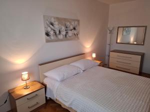 a bedroom with a bed and two night stands and a mirror at Apartments with swimming pool Poljica, Zadar - 13838 in Vrsi