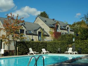 a swimming pool with two lawn chairs and a house at Apt w Fireplace & Garden in Durbuy